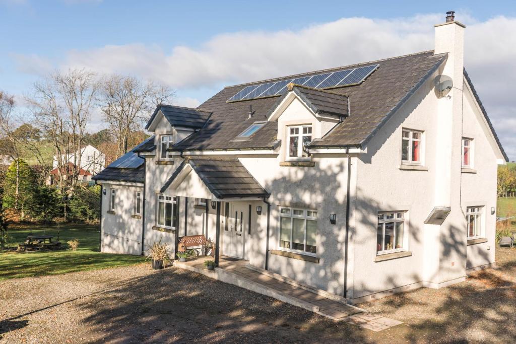 une maison blanche avec des panneaux solaires sur son toit dans l'établissement Dunroamin Bed & Breakfast, à Drymen