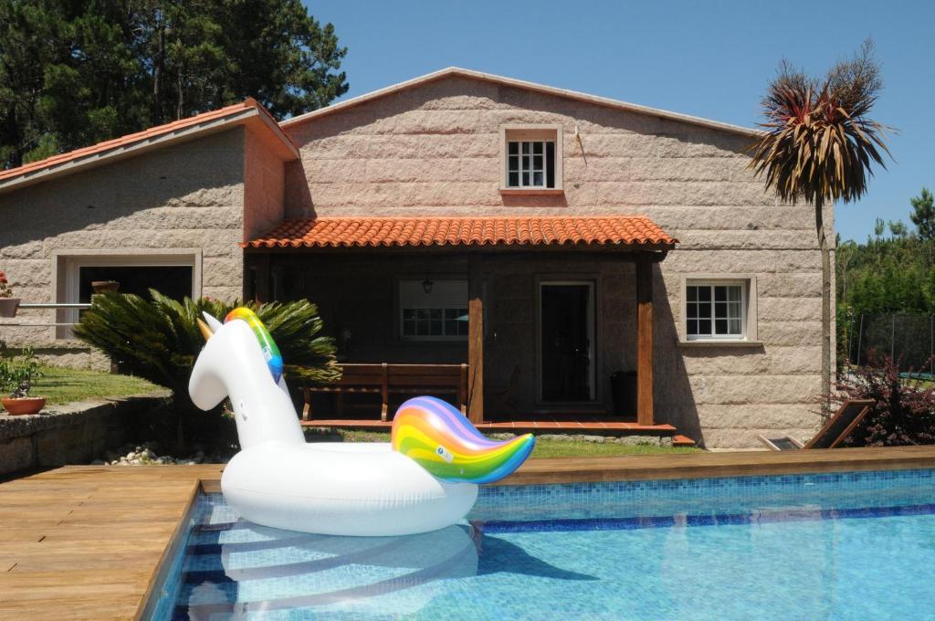 uma piscina com um cisne insuflável em frente a uma casa em Villa Cuesta em O Grove