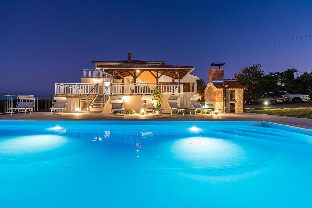 a swimming pool in front of a house at night at Vila Luna Apartments in Zadar