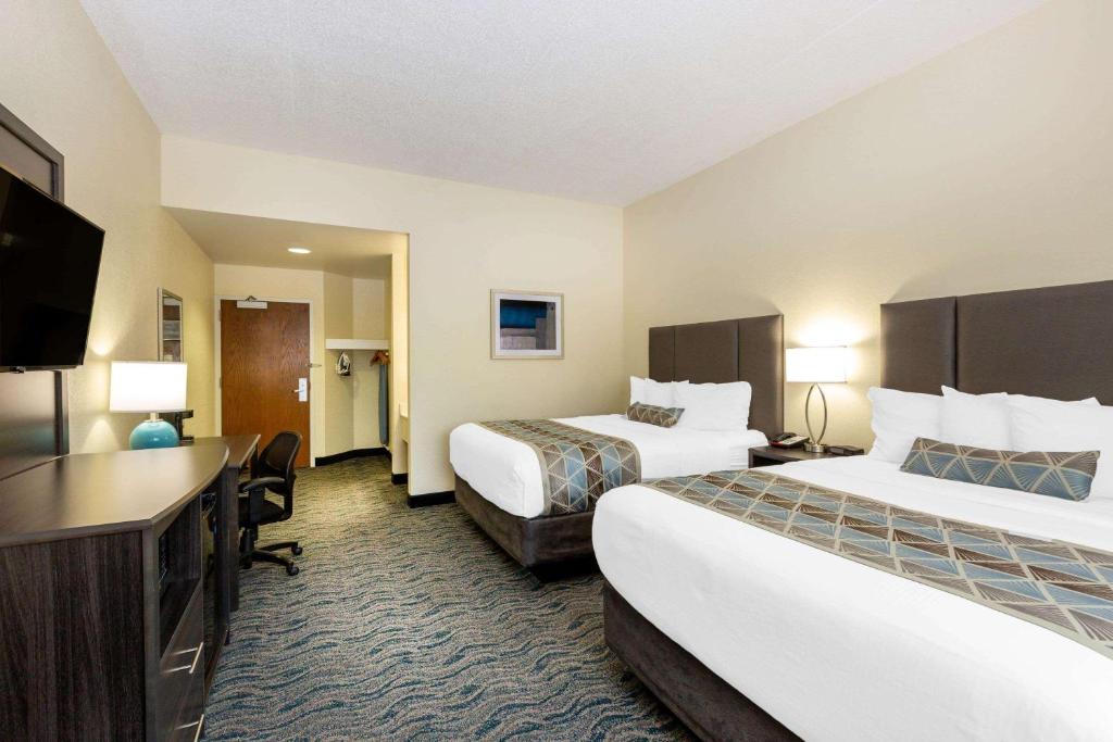 a hotel room with two beds and a flat screen tv at Baymont by Wyndham Des Moines Airport in Des Moines