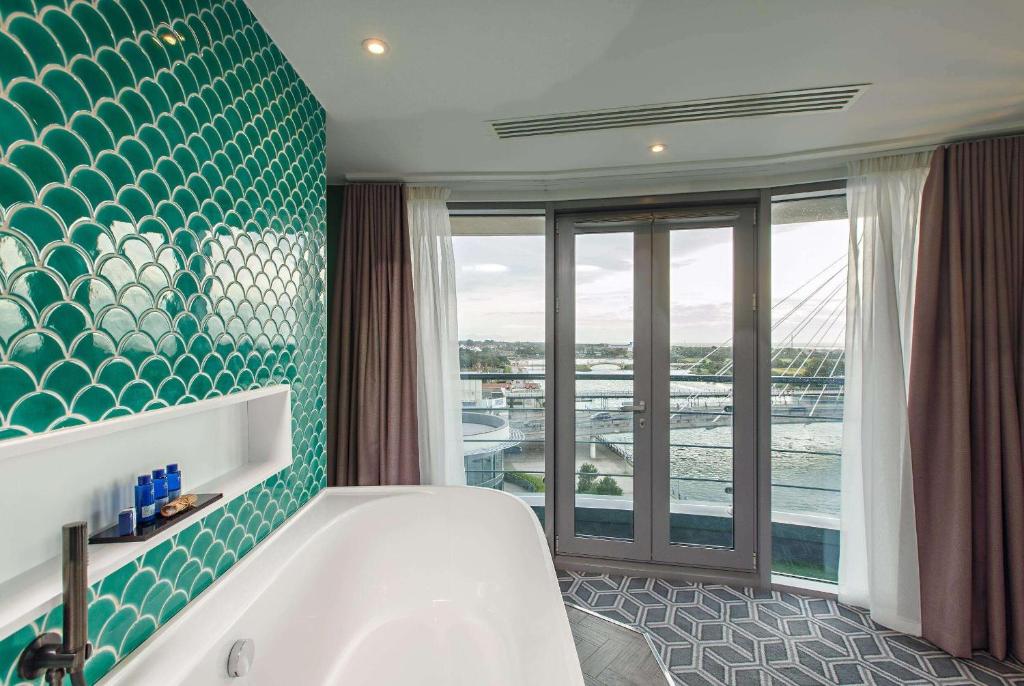 a bathroom with a tub and a large window at Waterfront Southport Hotel in Southport