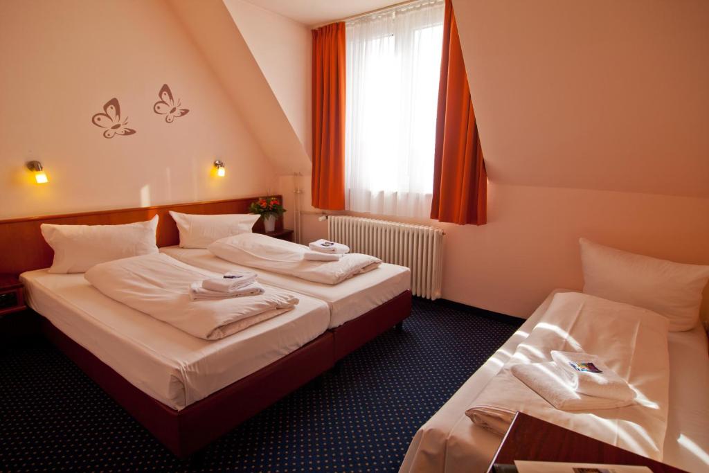 a hotel room with two beds and a window at Hotel Residenz in Düsseldorf