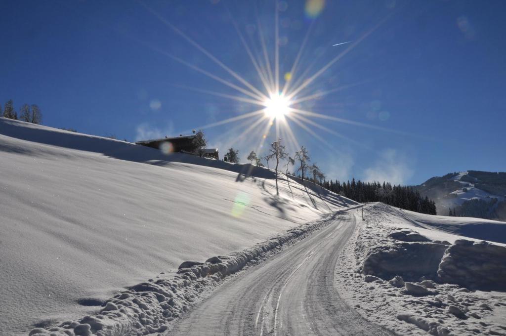 a snow covered slope with the sun in the sky at DAS "ZwisleggGut" in Wagrain