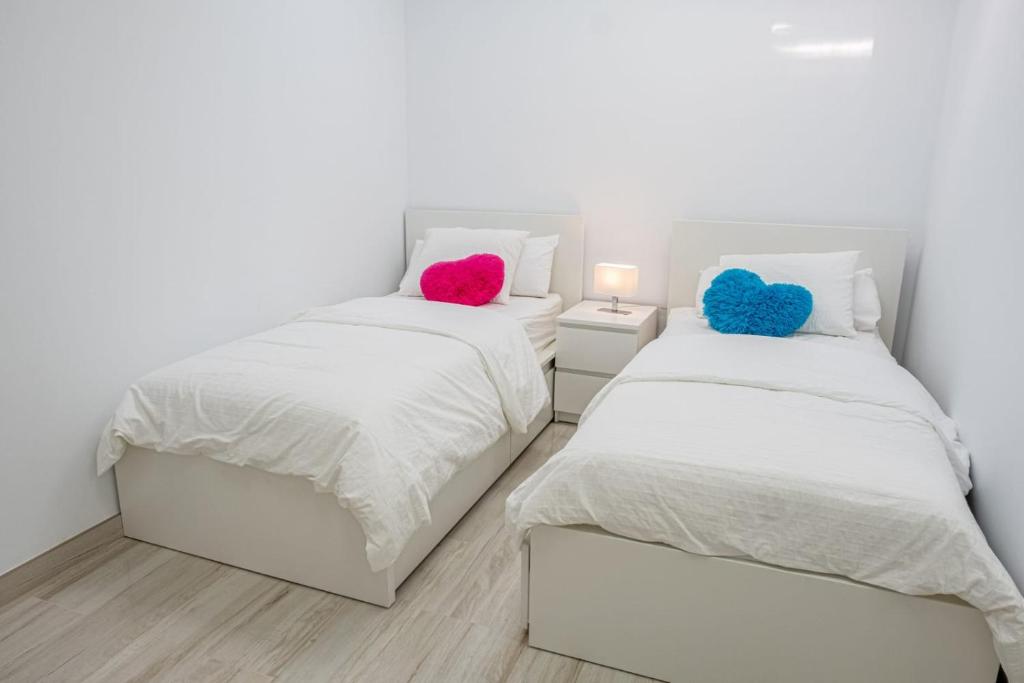 two beds in a bedroom with white walls and colorful pillows at Villa del Mar Esquinzo Jandia Fuerteventura in Playa Jandia