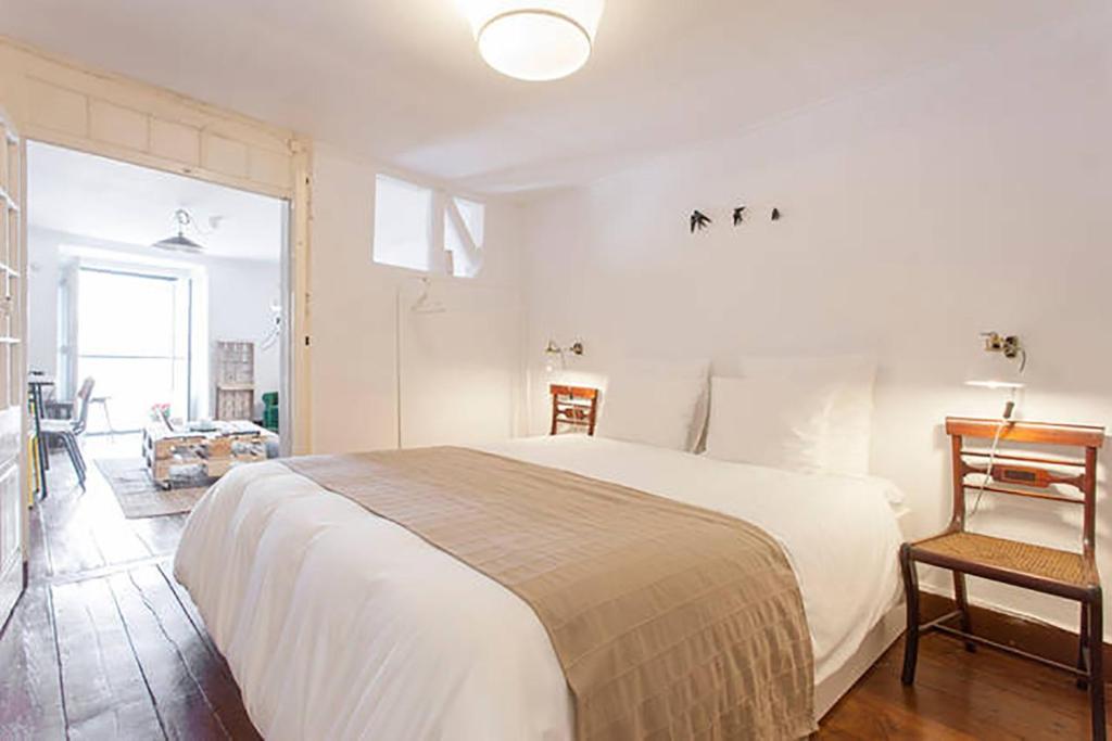 een slaapkamer met een groot wit bed en een stoel bij Oak Valley Flats Bairro Alto in Lissabon