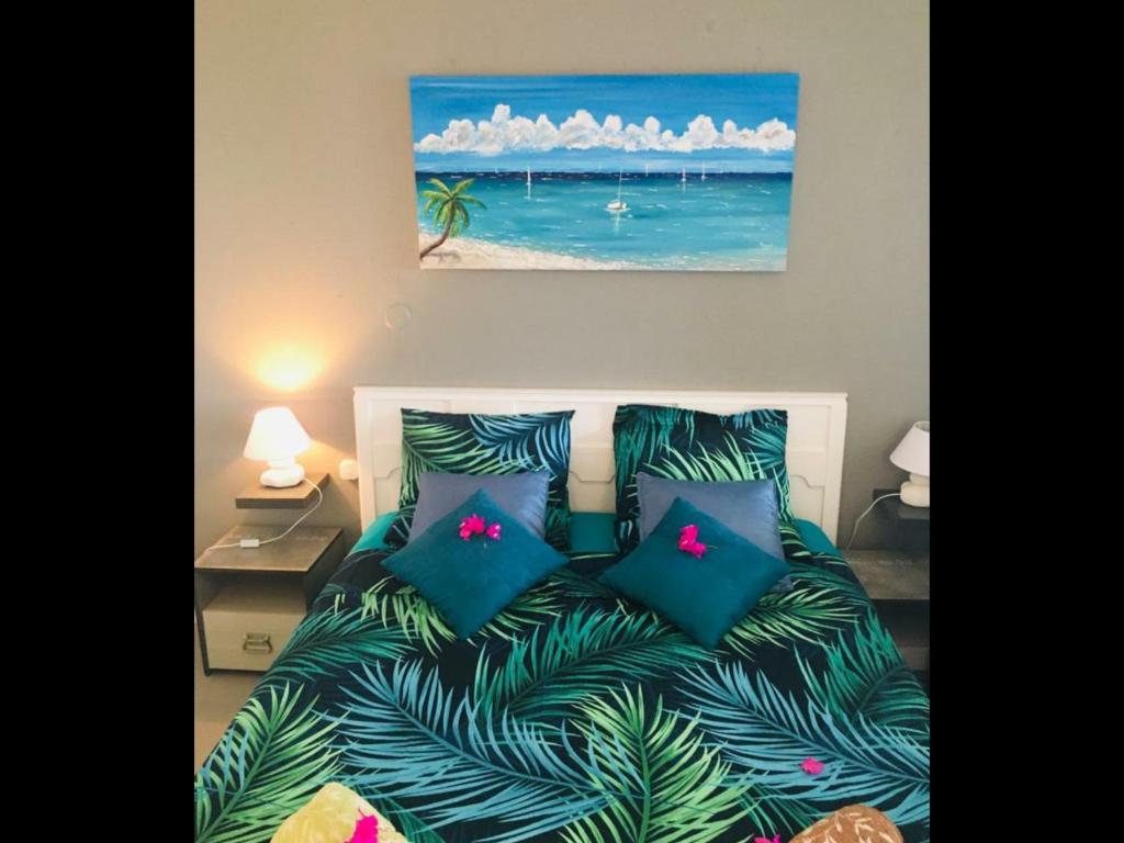 - un lit avec des oreillers bleus et une photo de l'océan dans l'établissement Appartement vue mer Anse des rochers, à Saint-François