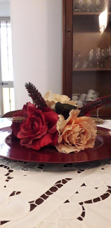 un plato con tres rosas en una mesa en Sa Domu Antiga, en Solarussa