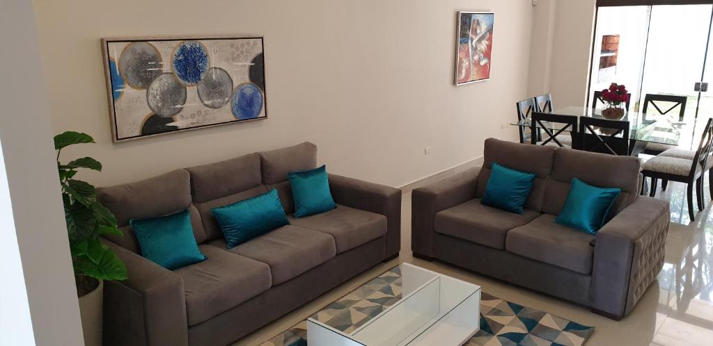 sala de estar con 2 sofás marrones y almohadas azules en SOCRA Trinidad, en Asunción