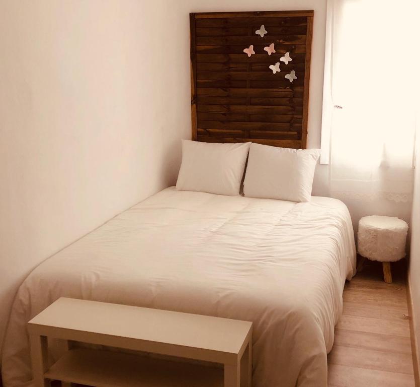 a small bedroom with a white bed and a bench at le petit caprice in Haro