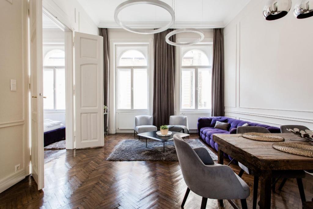 een woonkamer met een paarse bank en een tafel bij Opera Apartment with FREE parking, 2BR2BA, AC in Boedapest