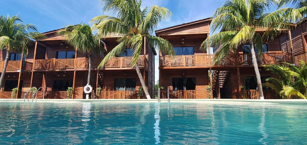 un complexe avec une piscine et des palmiers dans l'établissement Cabañas Coconut by MIJ, à Holbox