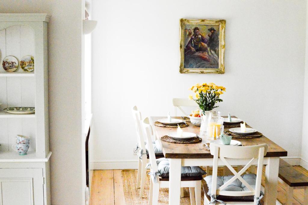 a dining room table with chairs and a painting on the wall at Mill Green Cottage, On site Pools & Spa access in Somerford Keynes