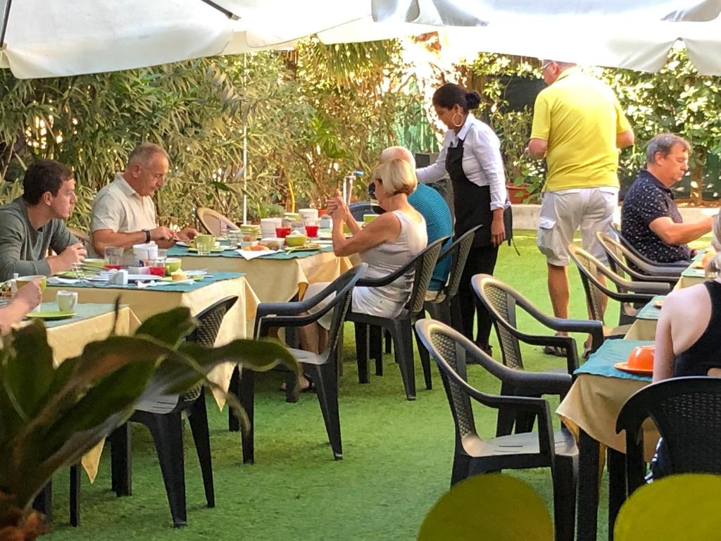 un grupo de personas sentadas en mesas bajo un paraguas en Villa Regina, en Riva del Garda