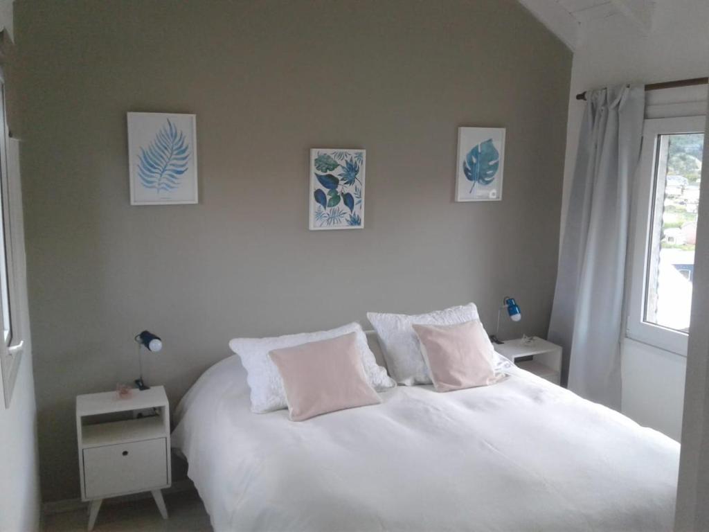 a bedroom with a white bed with pillows and a window at Mirador del Bosque Aparts in El Chalten