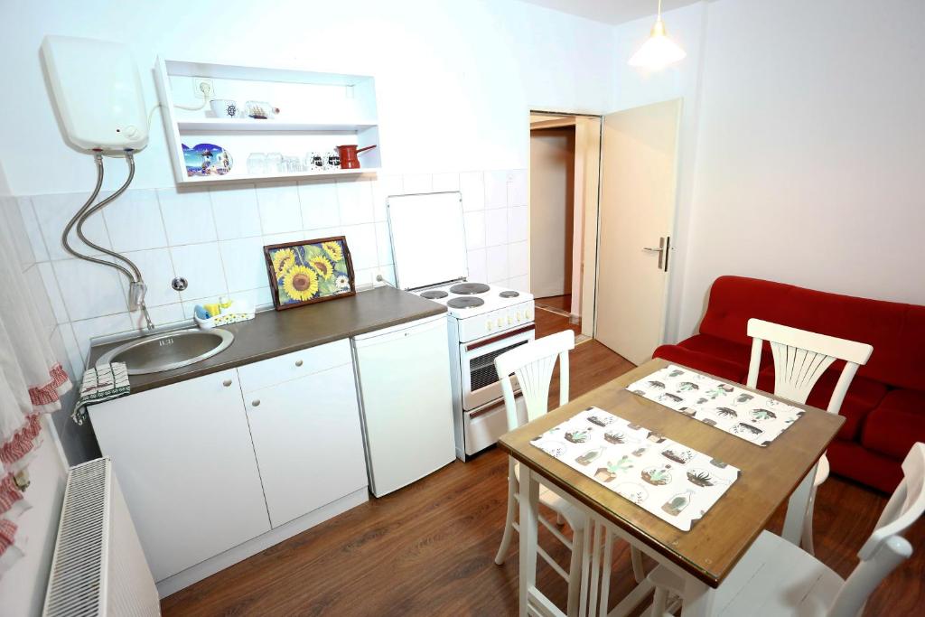 een kleine keuken met een tafel en een rode bank bij Apartman Carpe Diem in Zaječar