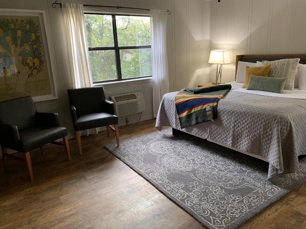 um quarto com uma cama, 2 cadeiras e uma janela em Loblolly Pines Adventure Cabin 2 King em Eureka Springs