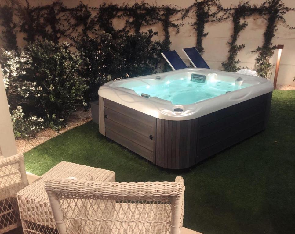 a jacuzzi tub in a yard with two chairs at Hotel Nautilus in Cagliari