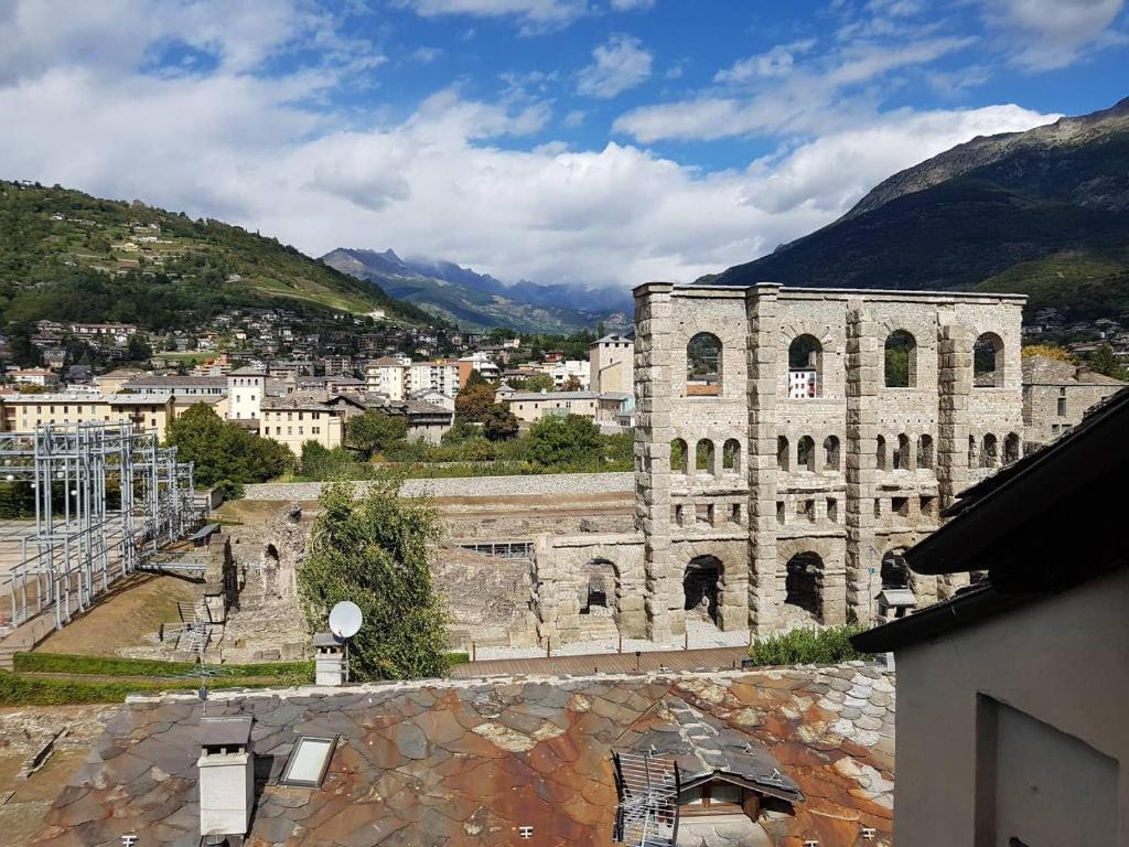 an old stone building with mountains in the background at Aosta con Vista - appartamento in centro in Aosta