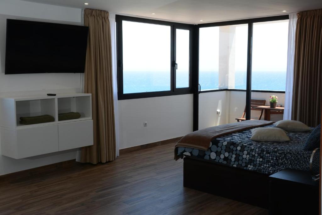 a bedroom with a bed and a tv and windows at Loft del Mar 2 Jandia in Playa Jandia