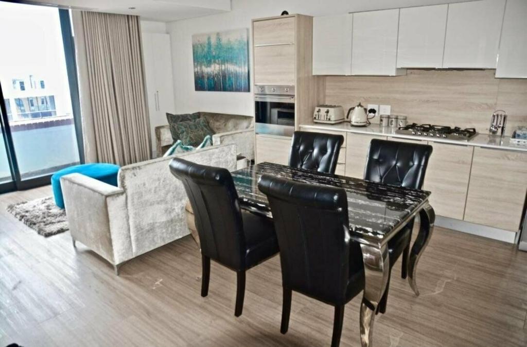 a kitchen and living room with a table and chairs at Matrix Luxury Apartments Century City, Cape Town in Cape Town