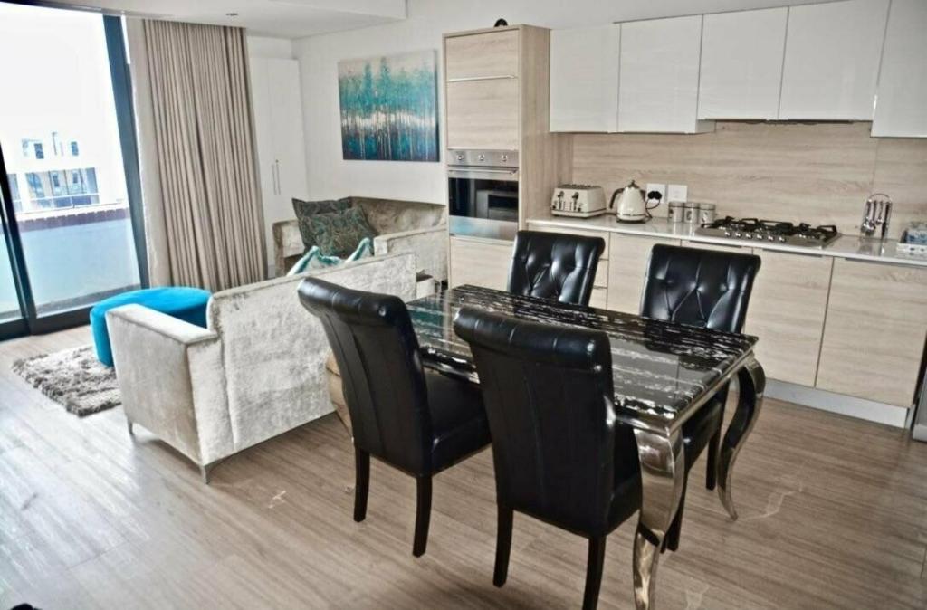 a kitchen and living room with a table and chairs at Matrix Luxury 2 bedroom Apartments Century City, Cape Town in Cape Town