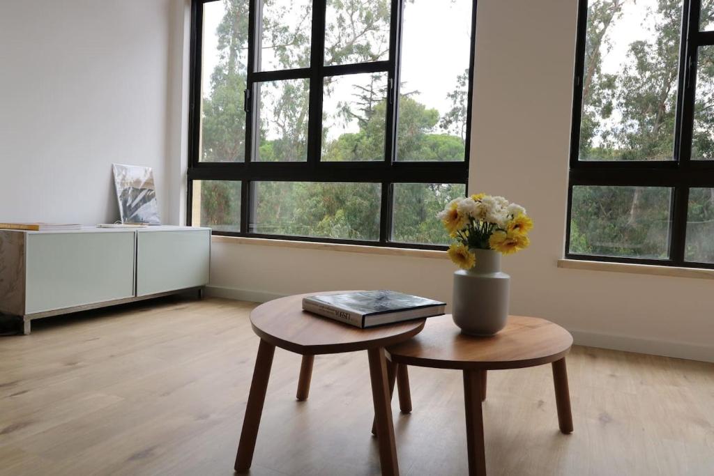 a room with a table and a vase with flowers on it at Treetops Lisbon Apartment in Lisbon