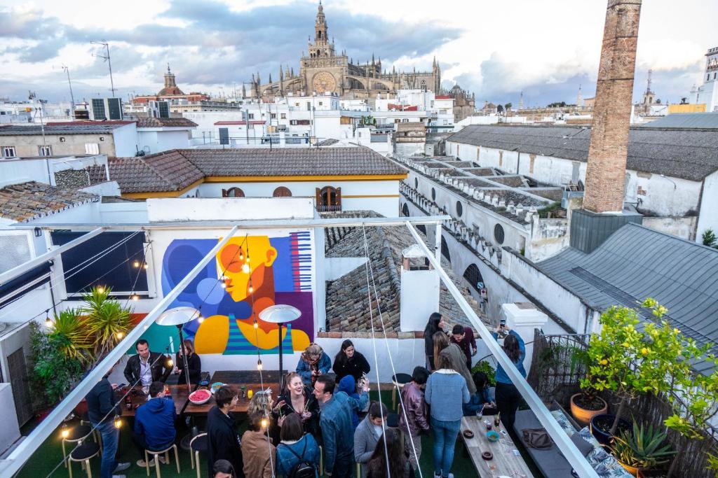 una multitud de personas de pie en la parte superior de un edificio en La Banda Rooftop Hostel, en Sevilla