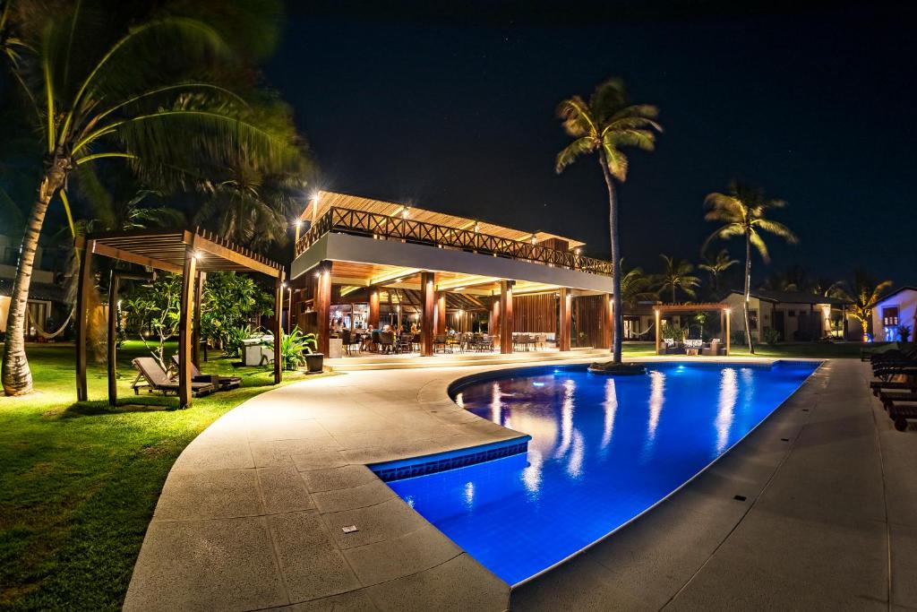 un complexe avec une piscine bleue la nuit dans l'établissement Vila Vagalume, à Trairi