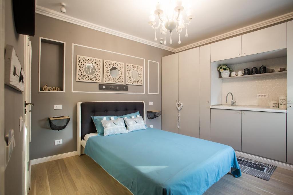 a bedroom with a blue bed and a kitchen at 62 Steps to Petit Bonheur in Bucharest