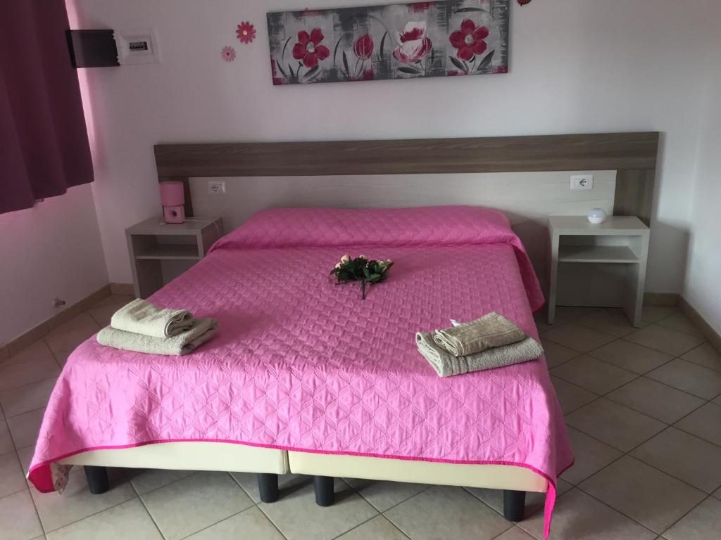 una camera da letto con un letto rosa e asciugamani di La Maison di Zia Annina in Sardegna a Olbia