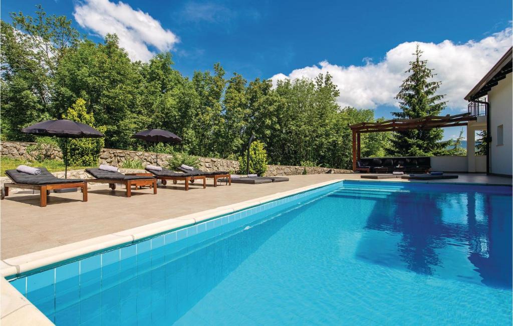 una piscina con bancos y sombrillas en un patio en Beautiful Home In Jurdani With Wifi, en Jurdani