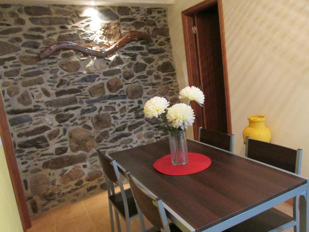 una mesa con un jarrón con flores blancas. en Casa Nazare en Vilar Torpim