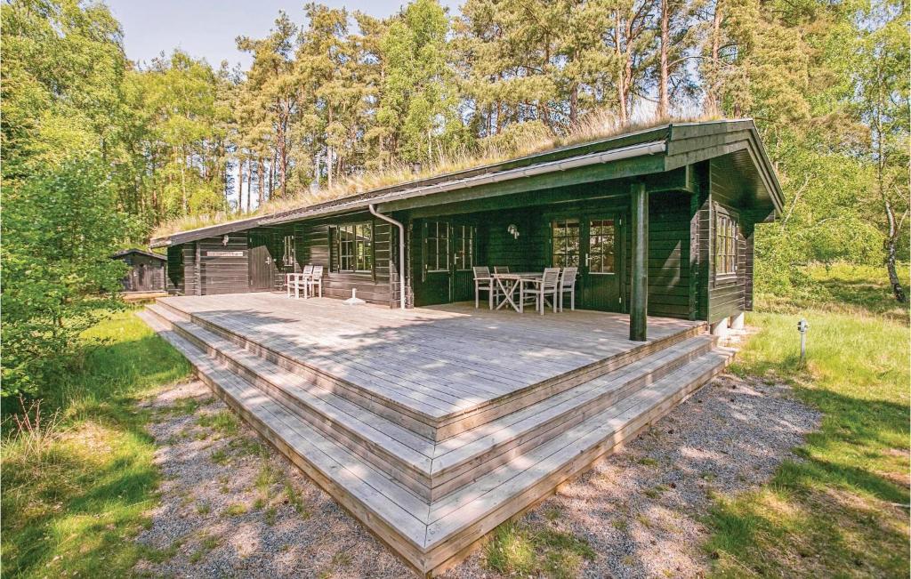 una baita di tronchi con un'ampia terrazza in legno di Pet Friendly Home In Nex With Kitchen a Spidsegård