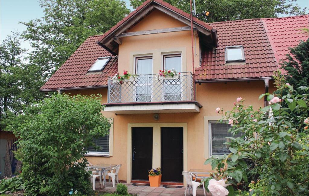 a yellow house with a balcony with flowers on it at Holiday Home Rewal Olszynowa in Rewal