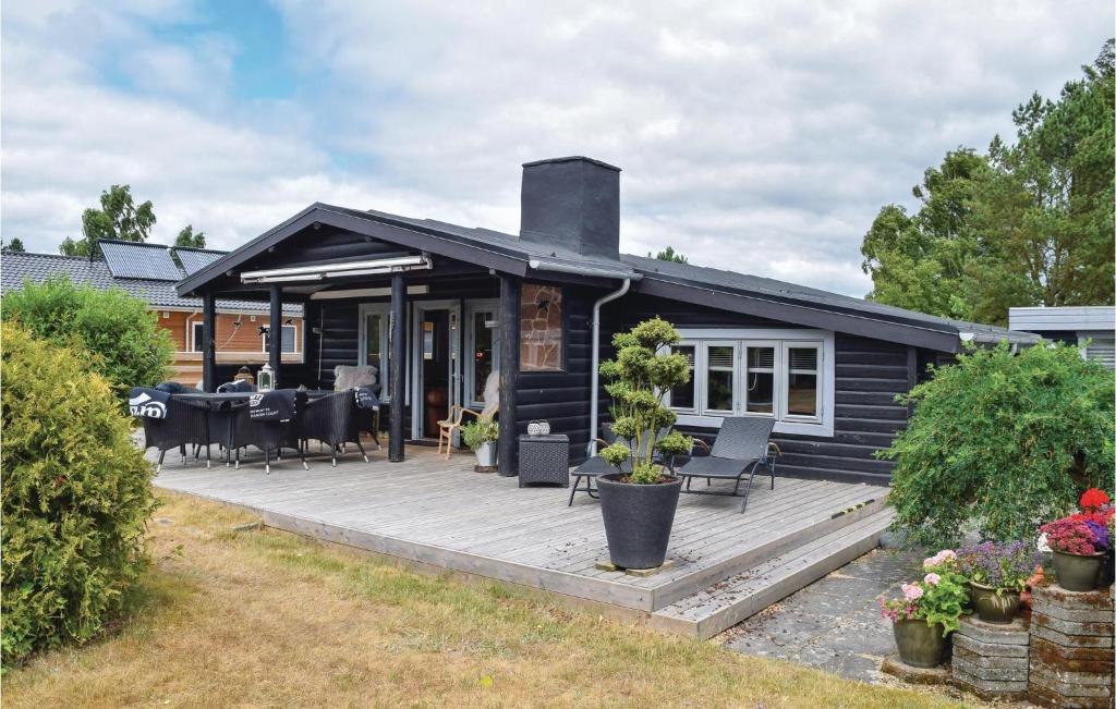 ein schwarzes Haus mit einer großen Holzterrasse in der Unterkunft 3 Bedroom Gorgeous Home In Juelsminde in Sønderby