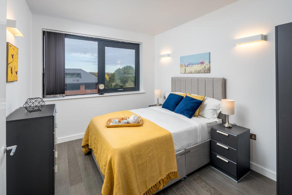 een slaapkamer met een bed met een gele deken en een raam bij St Albans City Apartments - Near Luton Airport and Harry Potter World in Saint Albans