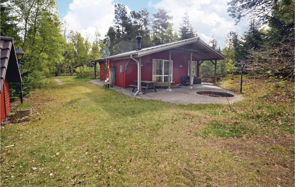 a red cabin with a deck in a field at Holiday Home Egelunden Hadsund Vi in Helberskov