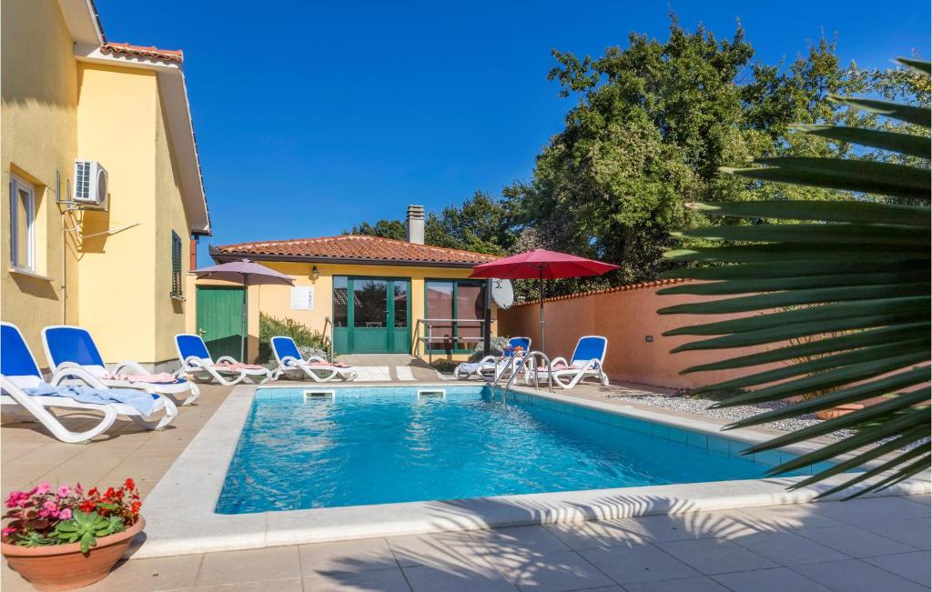 a swimming pool with chairs and umbrellas next to a house at 3 Bedroom Gorgeous Home In Labin in Labin