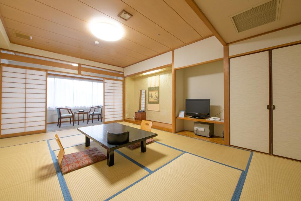a living room with a table and a dining room at Shuzenji Onsen Hotel Takitei in Izu