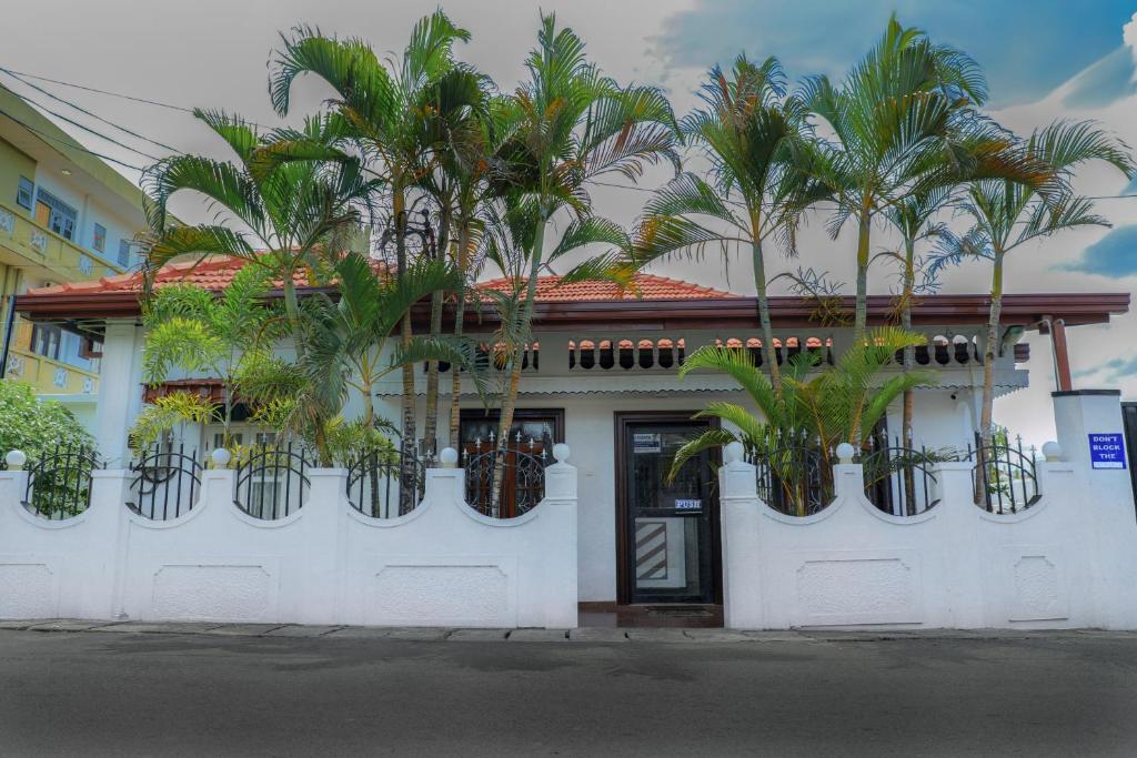ein weißes Gebäude mit Palmen in Pflanzen darauf in der Unterkunft Bon Voyaage Tourist Inn in Trincomalee