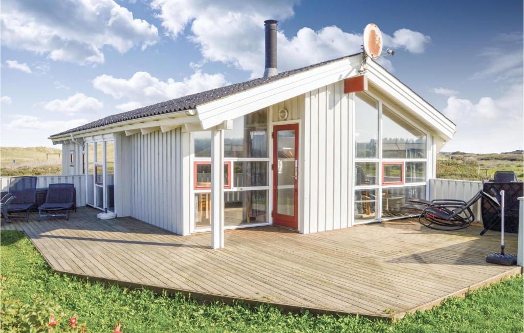 a white house with a wooden deck with chairs at Cozy Home In Hjrring With Sauna in Lønstrup