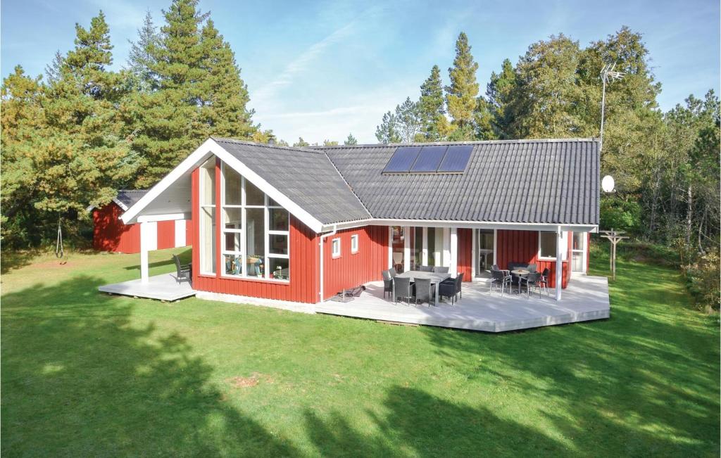 a red house with a solar roof on a yard at Nice Home In Oksbl With 4 Bedrooms, Sauna And Wifi in Mosevrå