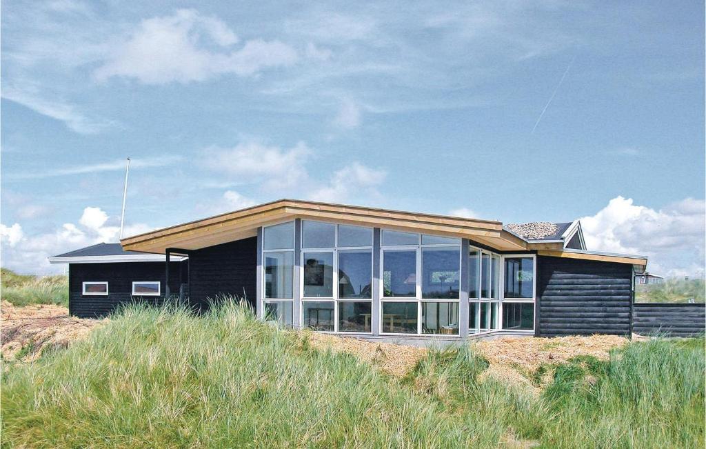 een klein zwart huis op een strand met hoog gras bij Cimbria in Fanø