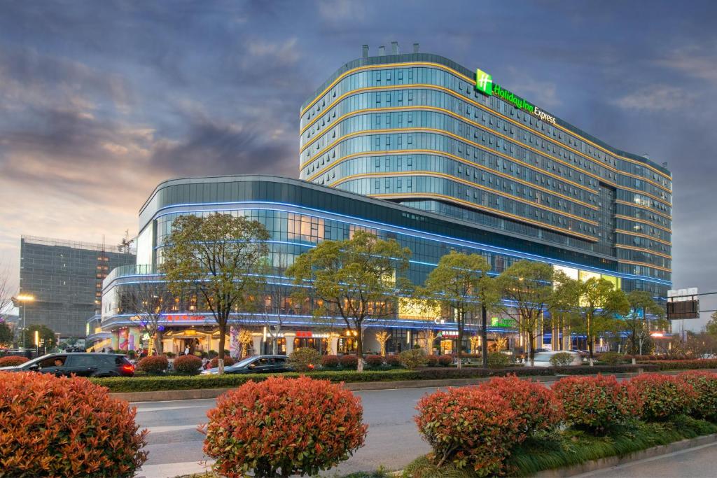 un edificio di vetro alto con un cartello verde di Holiday Inn Express Hangzhou East Station, an IHG Hotel a Hangzhou