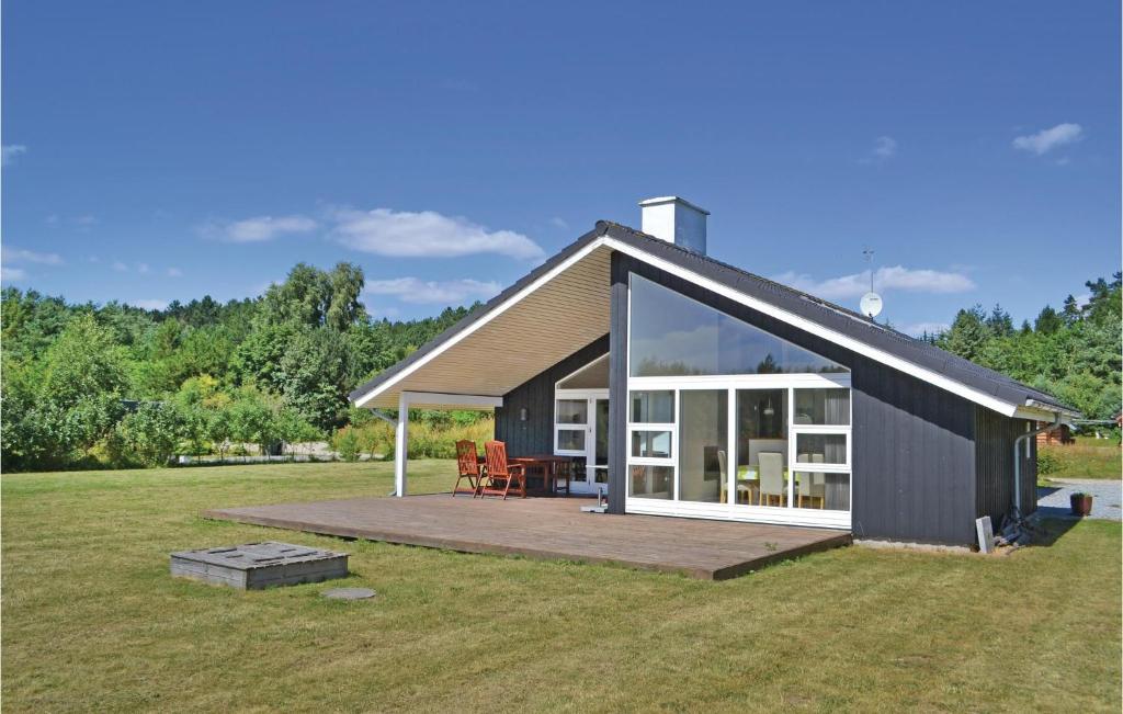 uma casa preta com um deque e uma grande janela em Sanglrken em Øksenmølle