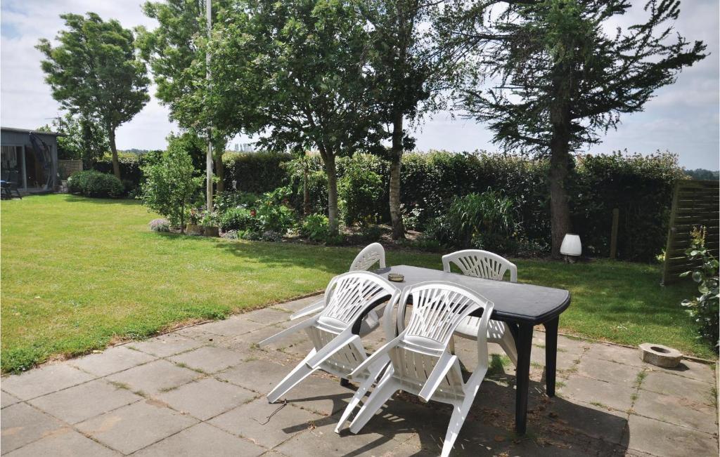 a table with four white chairs around it at One-Bedroom Apartment In Sydals in Tandslet