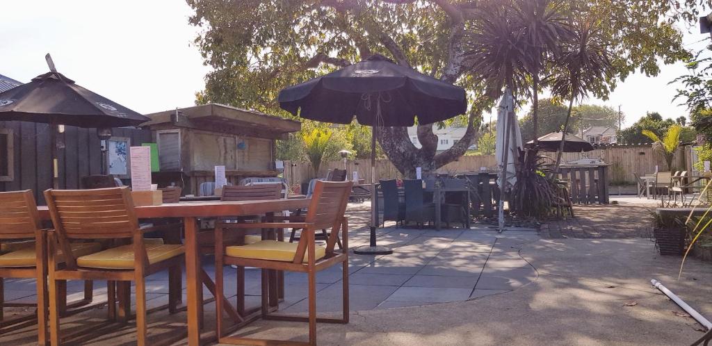 a wooden table with chairs and an umbrella at Talisman Hotel & Restaurant in Katikati