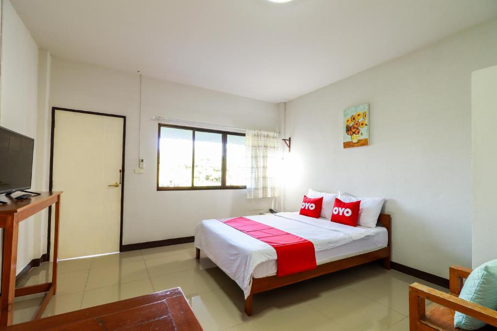Un dormitorio con una cama con almohadas rojas. en OYO 421 Dnk Baan Suan en Lamphun