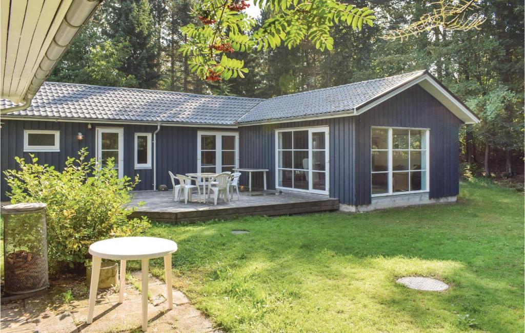 uma pequena casa azul com um deque e uma mesa em 2 Bedroom Cozy Home In Ebeltoft em Øksenmølle