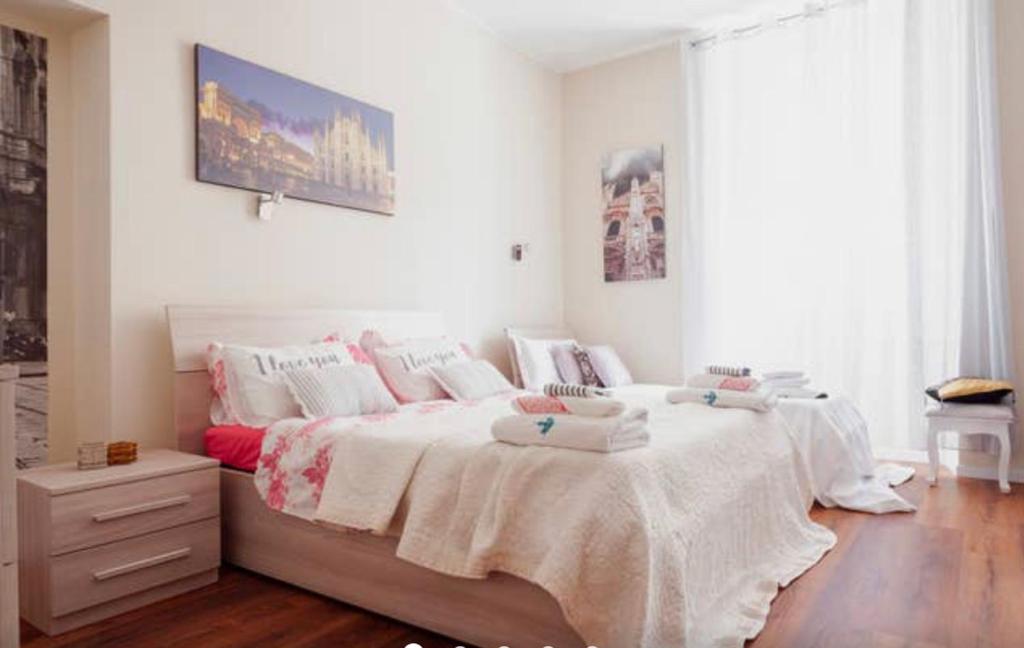 una camera da letto con un grande letto con lenzuola e cuscini bianchi di Rodica Comfort Home Milano Navigli a Milano